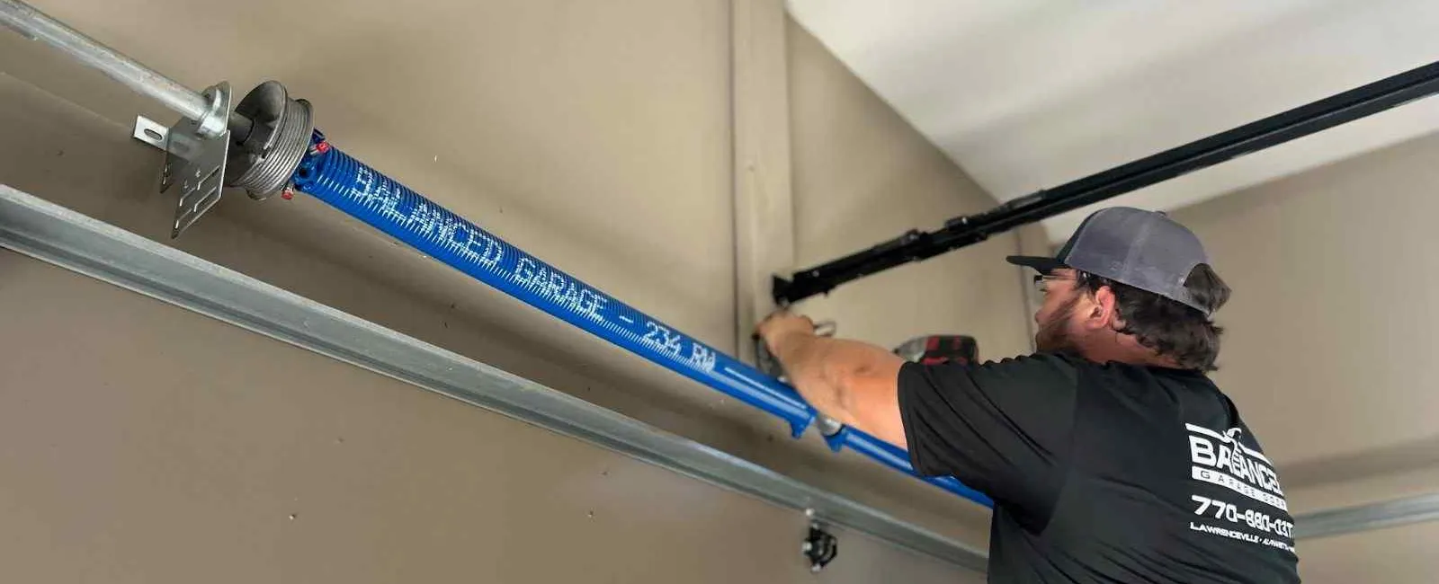 Technik instaluje prowadnice i sprężyny w bramie garażowej segmentowej