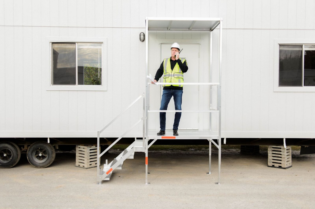 apteczka pierwszej pomocy i gaśnica zamontowane na ścianie baraku budowlanego