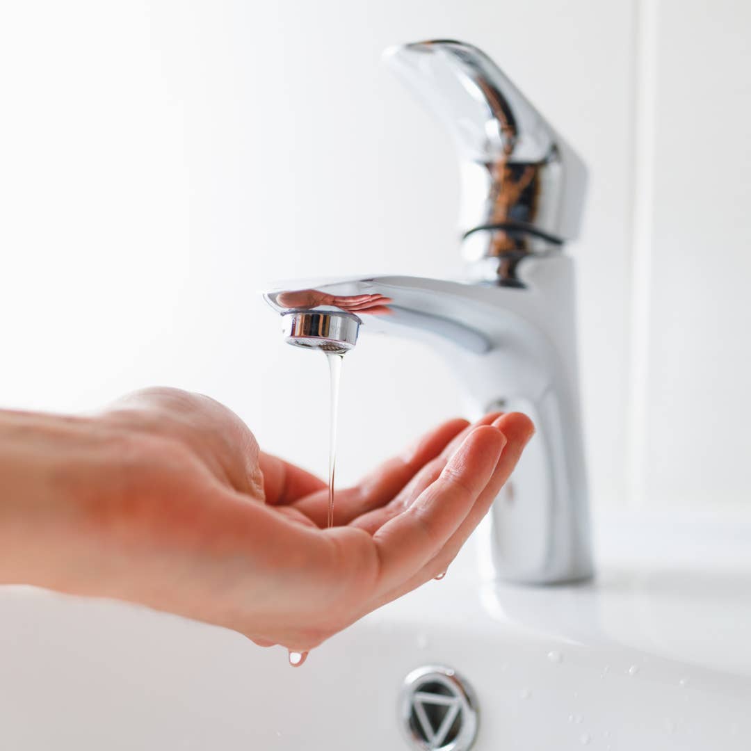 mocny strumień wody tryska z kranu rozpryskując krople na blacie