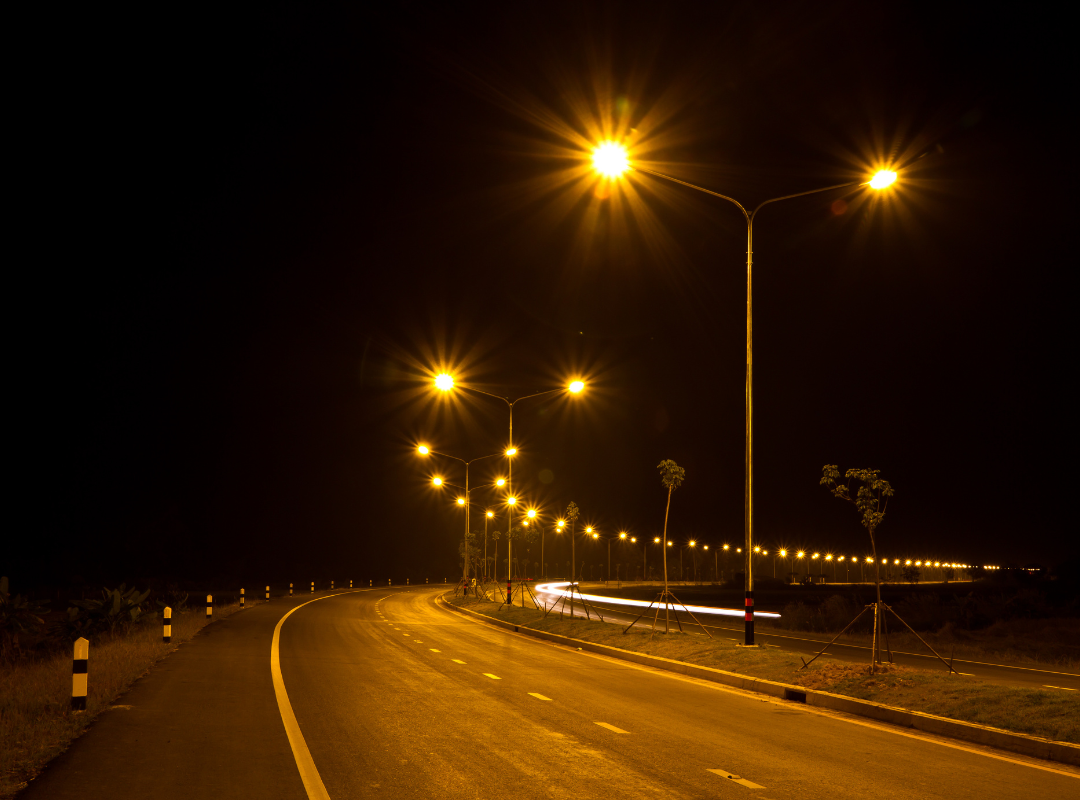 rząd wysokich słupów z lampami sodowymi wzdłuż ruchliwej arterii