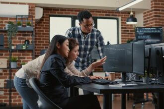 mały zespół programistów w jasnym biurze pracujący z laptopami nad projektem
